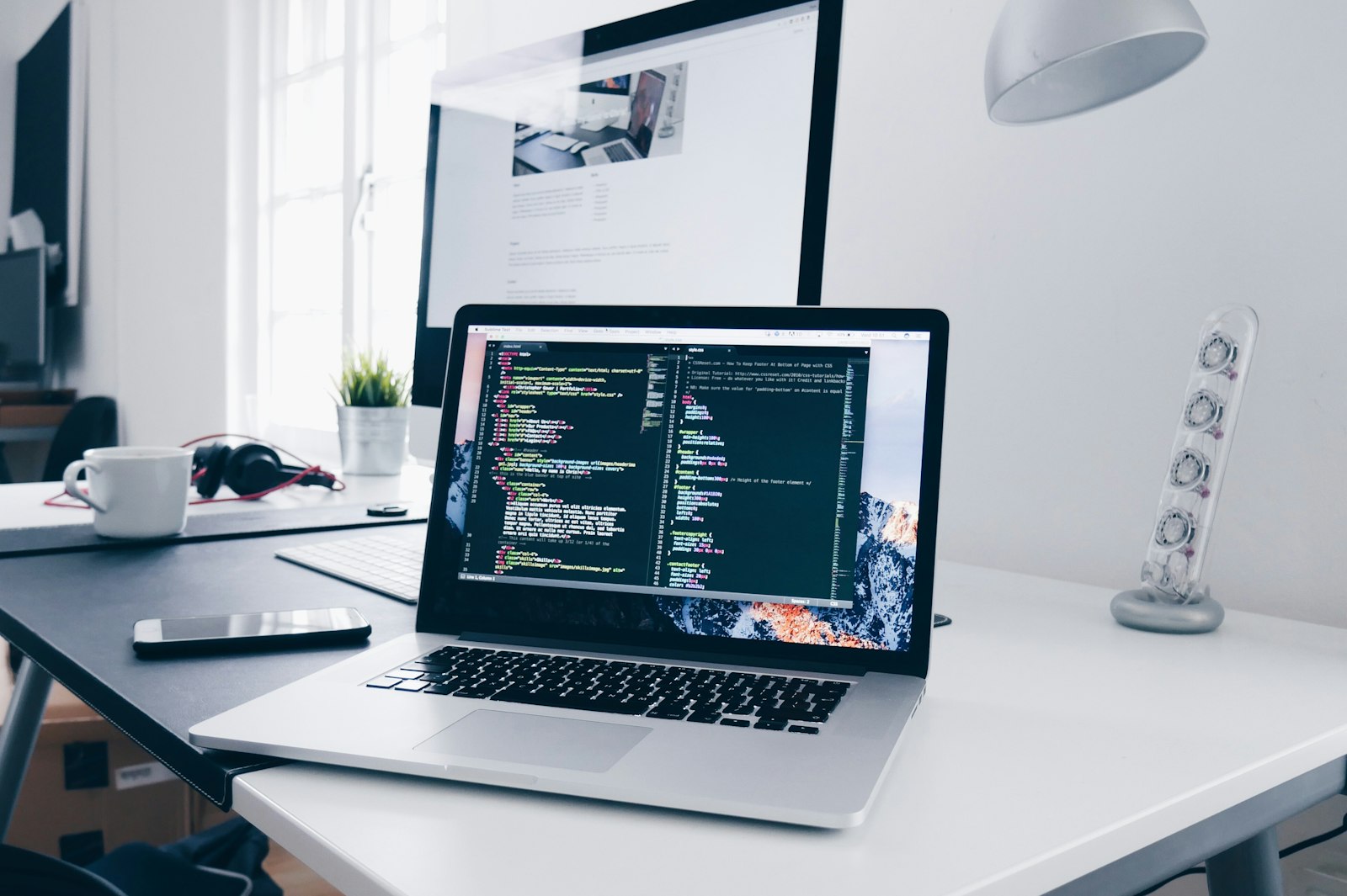 Notebook aberto sobre uma mesa, com o código de um site na tela.
